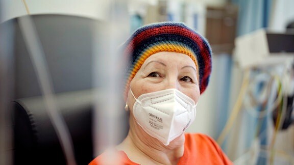 Inge Thomas hat Lungenkrebs, unheilbar. Sie trägt eine Mütze und einen Mundschutz.