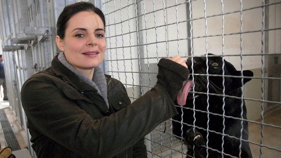 Dr. Susanne Mertens (Elisabeth Lanz) lässt den schwarzen Panther an ihrer Hand lecken - das Gitter des Käfigs trennt sie von der Raubkatze.