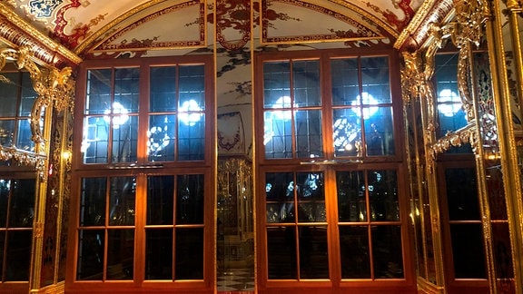 Eine Fensternische mit goldenen Verzierhungen und kunstvoll gemalten Wandbildern.
