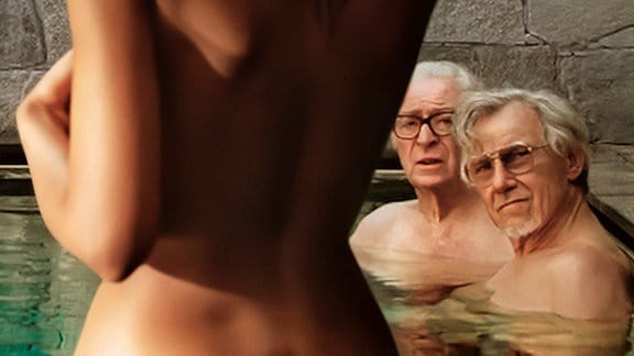 Eine junge nackte Frau steigt in einen Pool und wird dabei von zwei älteren Männern beobachtet.