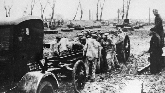 KZ-Zwangsarbeiter werden von Wachleuten beobachtet.