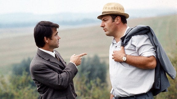 Zwei Männer stehen auf einem Feldweg und unterhalten sich.