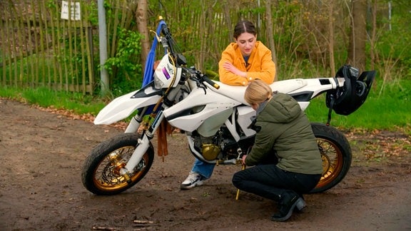 Jördis (Diana Staehly) hat eine Panne und repariert das Motorrad selbst. Leyla ist beeindruckt (Alinda Yamaci).