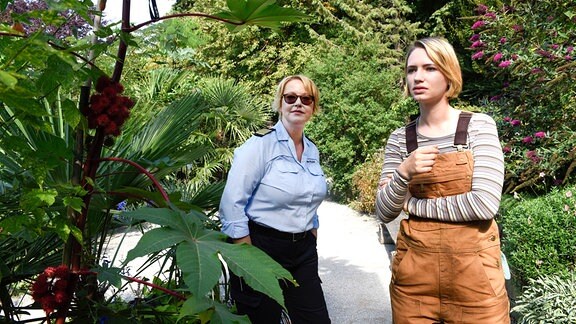 Denise Munk (Zoë Valks, r.) erklärt Nele Fehrenbach ( Floriane Daniel, l.), wie man aus dem Wunderbaum Gift extrahieren kann.