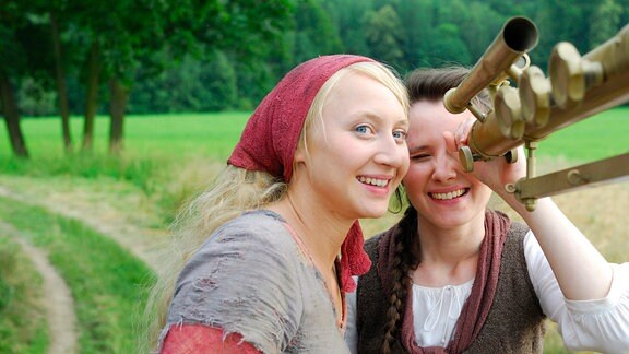 Die kluge Bauerntochter (Anna Maria Mühe) und ihre Freundin die Magd (Sabine Krause) bestaunen das Fernrohr des Königs.