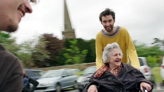 Junger Mann mit Großmutter im Rollstuhl