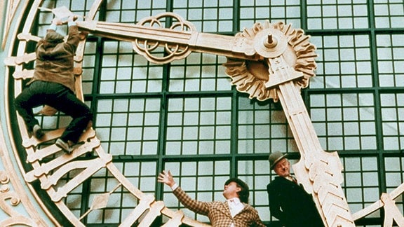 Egon Olsen (Ove Sprogoe), Benny (Morten Grunwald) und Kjeld (Poul Bundgaard, v.l.n.r.) hängen an der Turmuhr des Kopenhagener Rathauses.