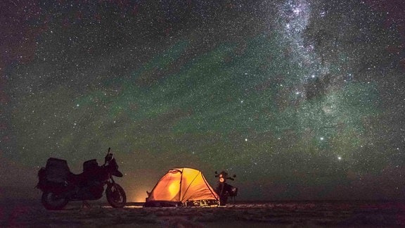 Das einsame Zelt der Reisenden auf der Salzebene in Bolivien mit einem faszinierenden, sternenübersäten Nachthimmel.