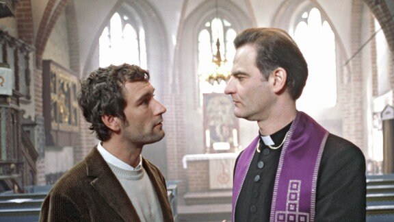 Ein Geistlicher und ein Mann in einer Kirche.