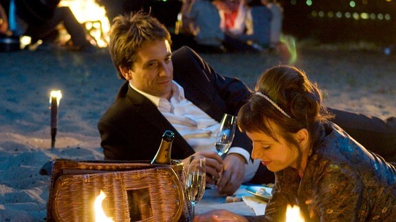 Siegfried (Oliver Mommsen) und Sandra (Julia Koschitz)  liegen bei Kerzenlicht am Strand.