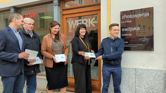 Fünf Menschen halten Namensschilder vor einem Ladengeschäft in Bautzen