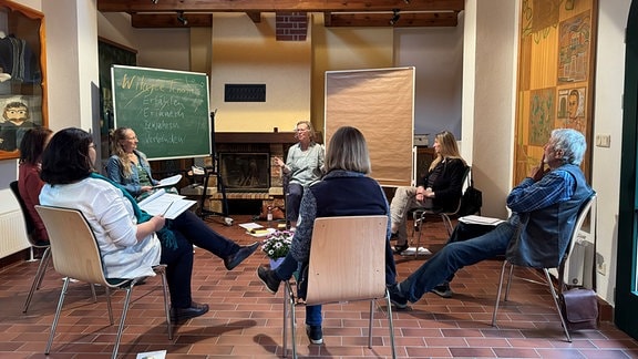 Sechs Menschen sitzen in einem Schulungsraum im Kreis.