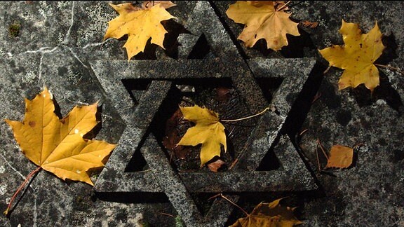Herbstlaub auf einer Grabplatte mit einem Davidstern auf dem jüdischen Friedhof in Erfurt