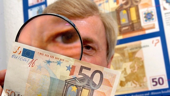 Ein Falschgeldexperte untersucht einen 50-Euro-Schein.