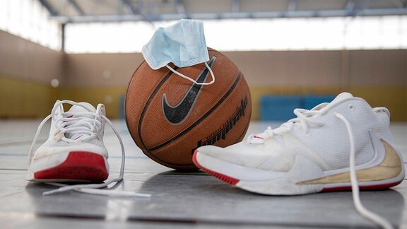 Sportschuhe, Basketball und eine Mund-Nasenmaske.