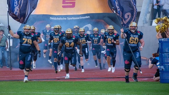 Spieler einer amarican Football-Mannschaft laufen auf das Spielfeld.