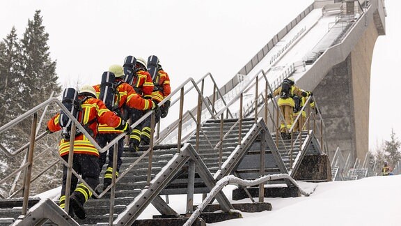 Feuerwehr-Teams bei einem Treppenlauf an einer Skischanze