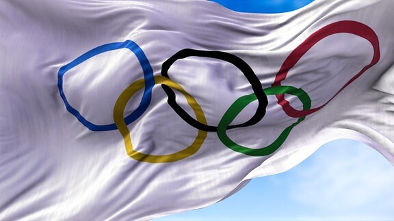 Eine Flagge mit dem Aufdruck der olympischen Ringe weht im Wind.