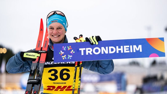 Skilangläuferin Victoria Carl hält lächelnd ein Schild mit dem Wort Trondheim .