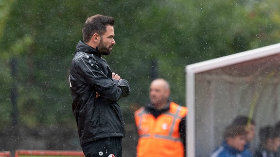 Trainer Benjamin Duda steht im Regen.