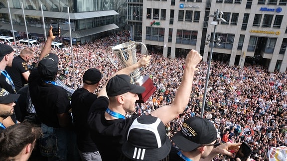 Spieler des Basketballteams Niners Chemnitz stehen feiernd auf dem Balkon des Rathauses.