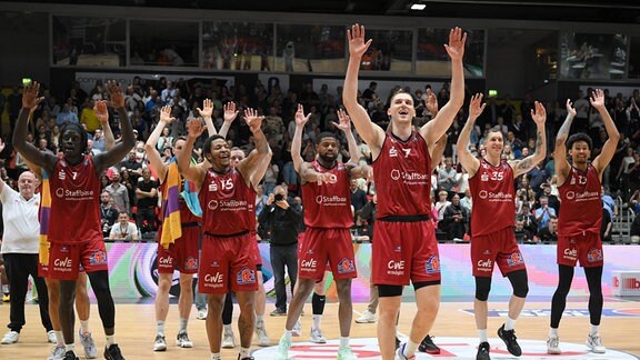 Basketballspieler jubeln mit erhobenen Armen.
