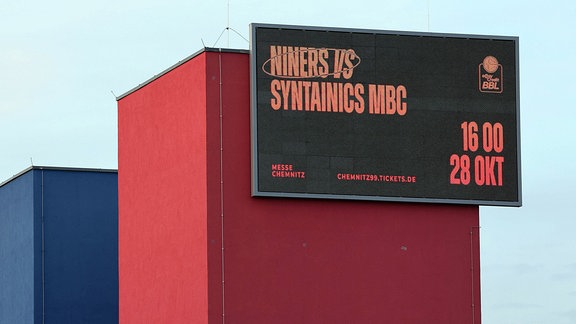 Digitaler Bildschrim an einem der Meesetürme am Einagng der Arena, mit der Info zum Spiel der Niners gegen Syntainincs MBC am 28. Oktober 2023.