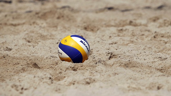Ein Volleyball liegt im Sand.