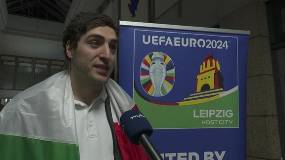 Handball-Spieler im Interview mit Italien-Fahne um den Schultern