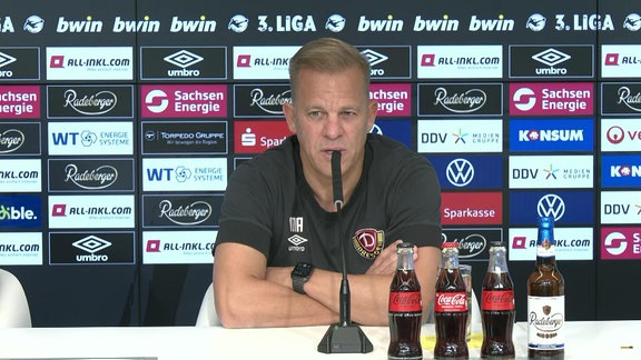 Dresden-Coach Markus Anfang auf einer Pressekonferenz vor einer Werbetafel
