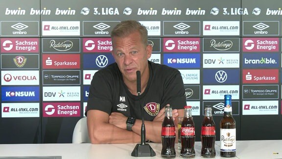 Dresden-Trainer vor einer Werbebande auf einer Pressekonferenz