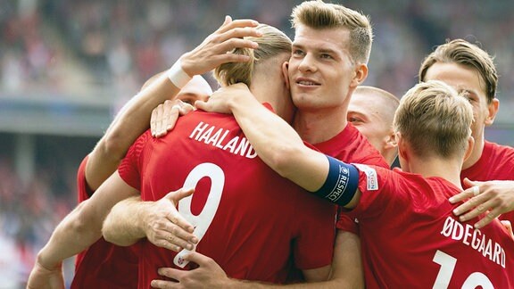 Norwegische Mannschaftskollegen umarmen Fussballer Erling Braut Haaland.