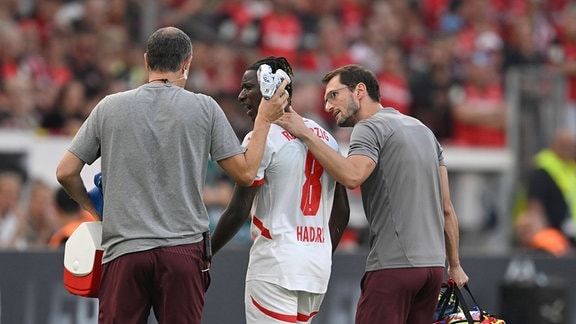 Amadou HAIDARA (L) nach seinem Kopftreffer, wird von Betreuern vom Platz gefuehrt