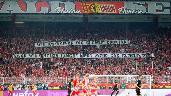 Fans des 1.FC Union mit Anti Red-Bull Transparent: WIR BETREIBEN DIE GLEICHE SPORTART. ABER WIR SPIELEN LÄNGST NICHT MEHR DAS GLEICHE SPIEL 