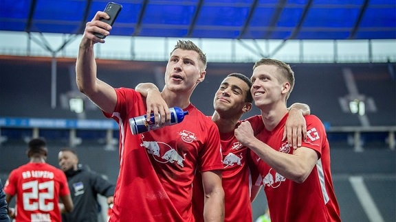 Willi Orban jubelt nach dem Spiel mit Tyler Adams und Dani Olmo und macht ein Selfie mit dem Handy.