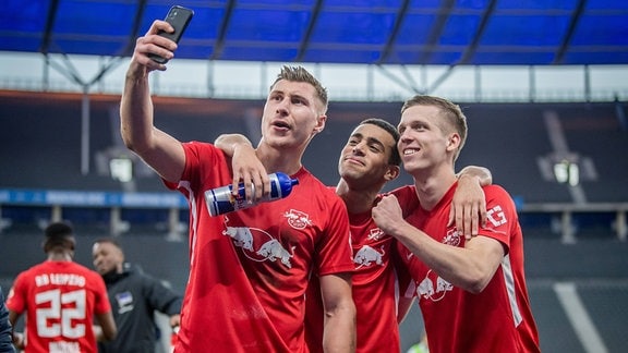 Leipzigs Willi Orban jubelt nach dem Spiel mit Tyler Adams und Dani Olmo und macht ein Selfie mit dem Handy