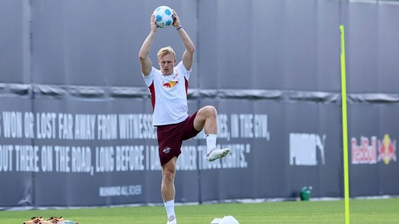 Xaver Schlager macht eine Übung mit dem Ball in der Hand auf einem Bein stehend auf dem Trainingsgelände von RB Leipzig