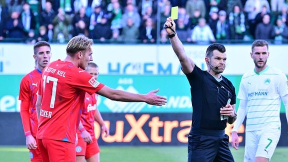 Alexander Sather (Schiedsrichter) zeigt Timo Becker (17, Holstein Kiel) die gelbe Karte