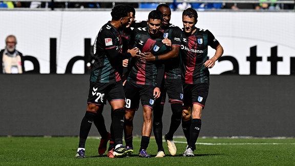 Jason Ceka, Livan Burcu und weitere Spieler des 1.FC Magdeburg jubeln.