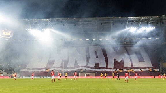 Fans von Dynamo Dresden präsentieren eine Blockfahne (die den gesamten K-Block abdeckt) mit der Aufschrift: DYNAMO. 