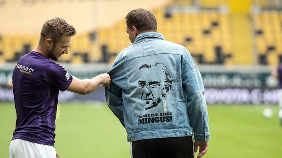 Dynamos Spieler tragen vor dem Erwärmen Jeansjacken mit dem Bild Ralf Minges und den Worten - DANKE FÜR ALLES MINGUS!
