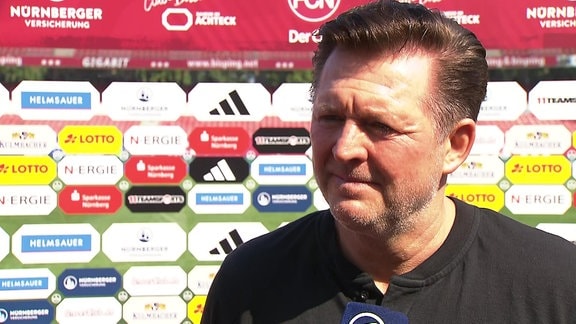 Trainer vor Werbebande im Interview