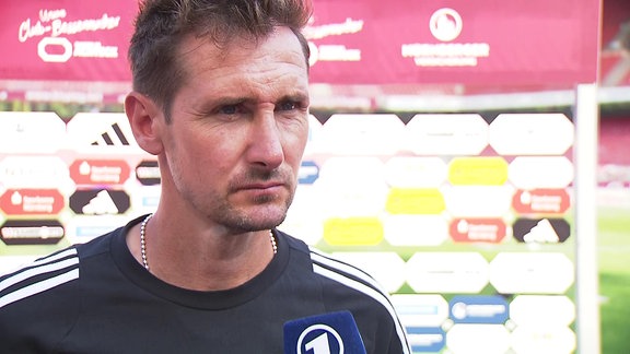 Trainer im Interview vor Werbebande