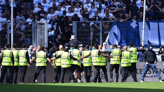 Während des Fußballspiels MSV Duisburg - FC Erzgebirge Aue  halten Security Fans von Duisburg vom betreten des Spielfelds ab.