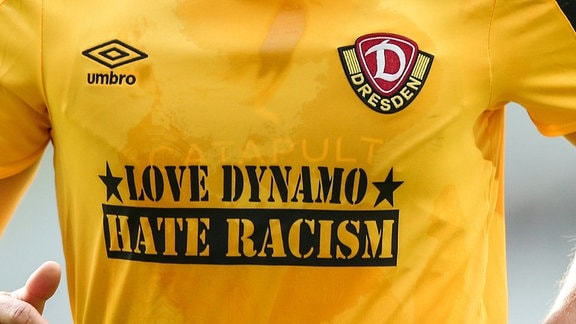 Nahaufnahme eines Spielers von Dynamo Dresden, der ein Trikot mit der Aufschrift "Love Dynamo Hate Racism" trägt.