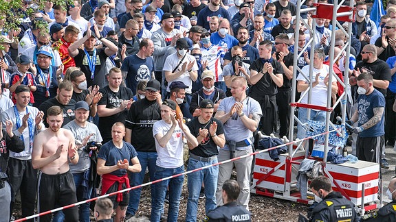 viele Fans des FC Hansa Rostock stehen vorm Stadion uind feuern die Mannschaft an.