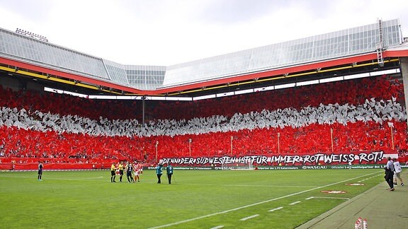 Fußballer im Stadion, die Tribünen sind rot und weiß beflaggt.