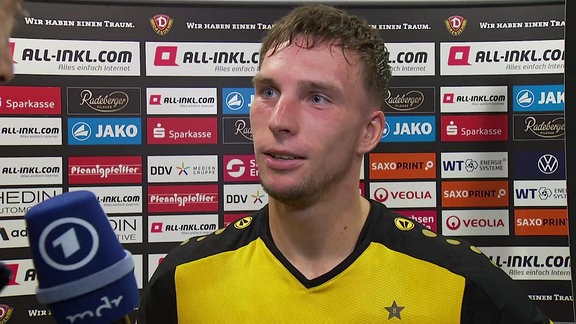 Spieler im Interview vor Werbebande