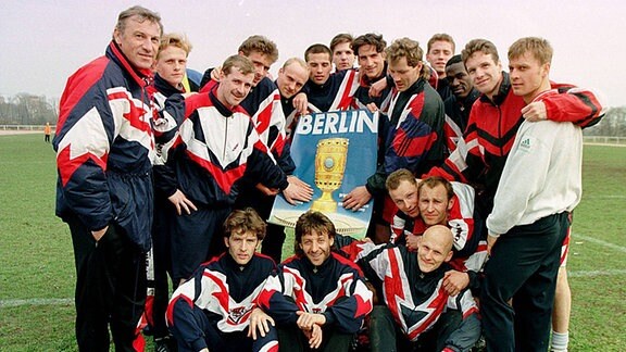 Coach Eduard Geyer und seine Spieler, u.a. Toralf Konetzke, Jens Melzig, Willi Kronhardt mit einem Plakat für das DFB-Pokalfinale in Berlin, 1997