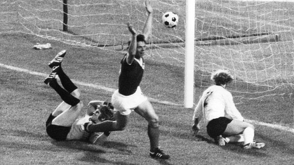 DDR-Stürmer Jürgen Sparwasser (M) von der jubelt am 22.06.1974 im Hamburger Volksparkstadion nach seinem Treffer zum 1:0 gegen die Bundesrepublik Deutschland mit erhobenen Armen, der geschlagene westdeutsche Torhüter Sepp Maier (l) und Verteidiger Berti Vogts (r) sind konsterniert.